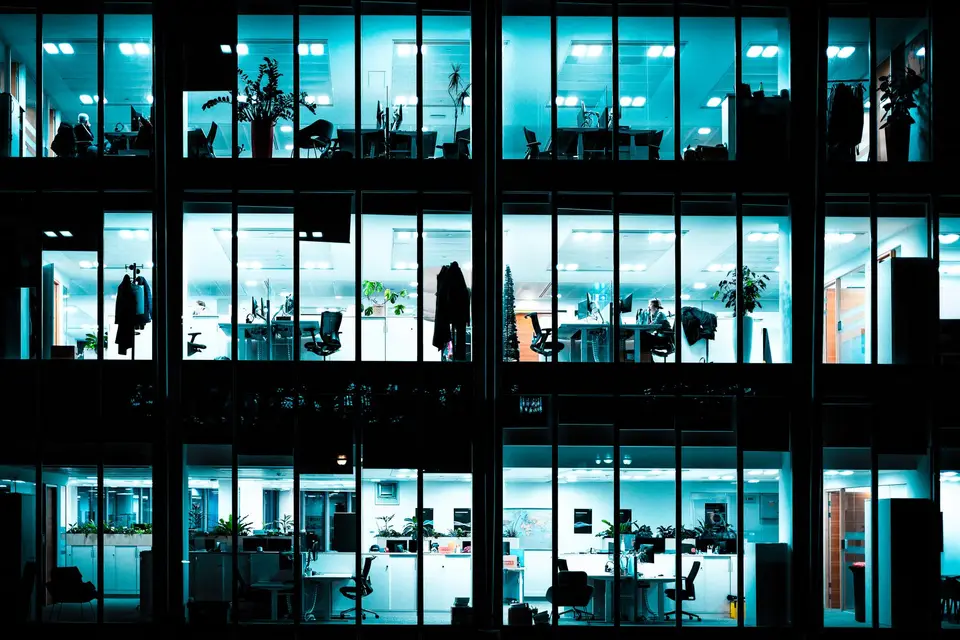 A modern office building at night, with rows of lit windows.