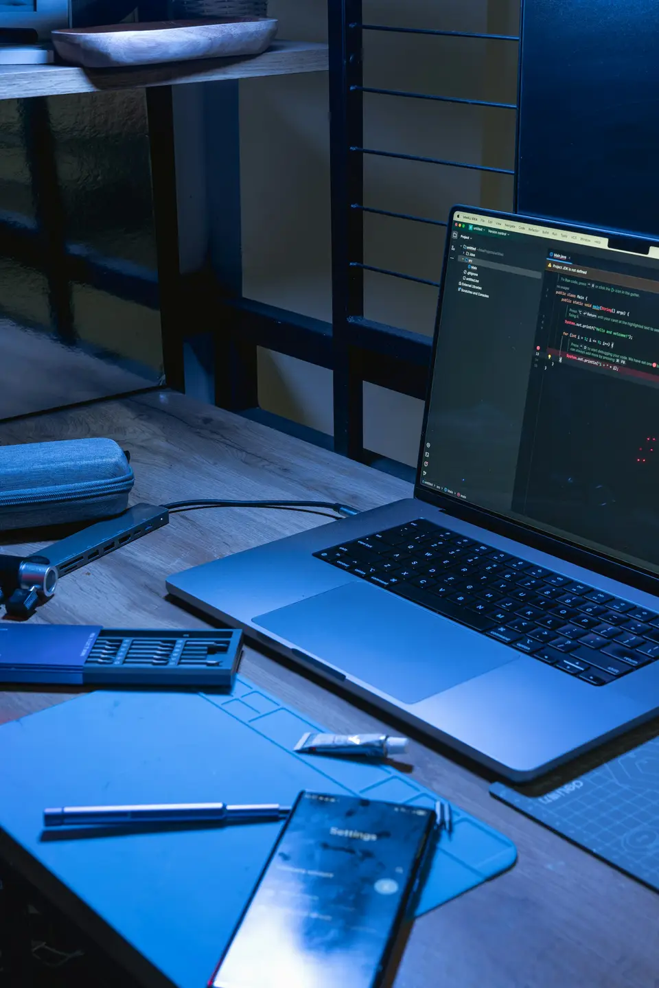 A laptop and a phone on a desk, both showing a code editor.