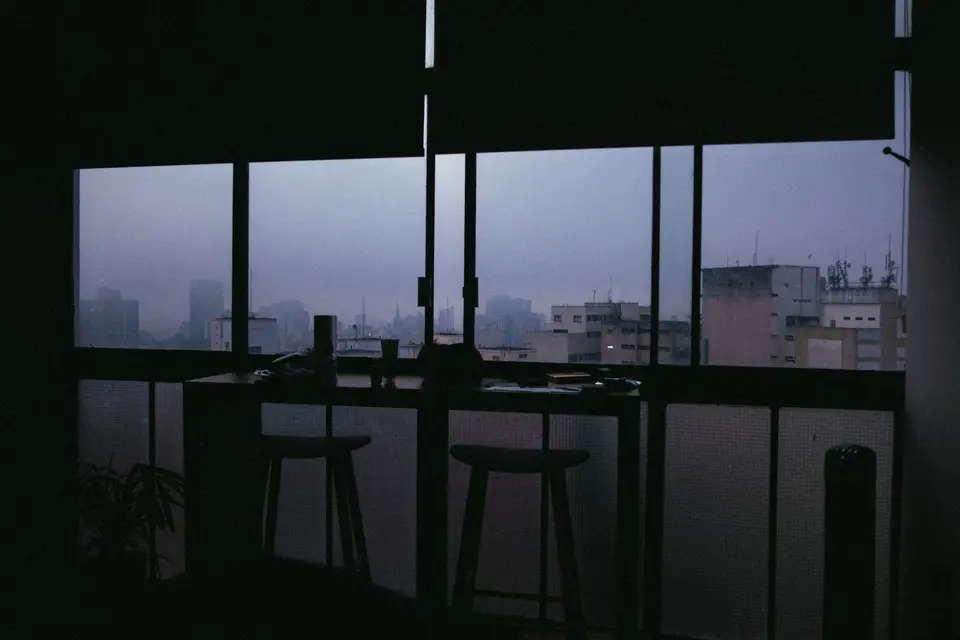 An office interior looking out through a window at a city skyline.